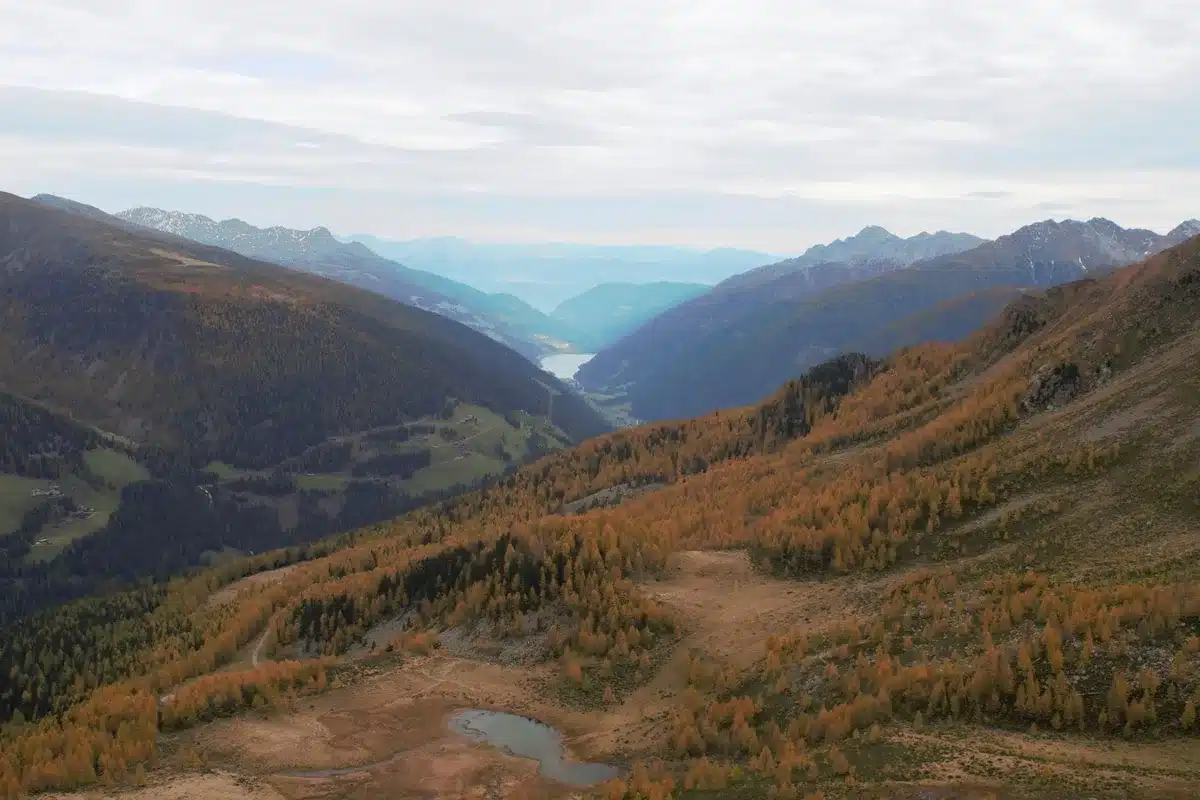 Herbstliche Berglandschaft mit Wanderweg durch Wald und Tal