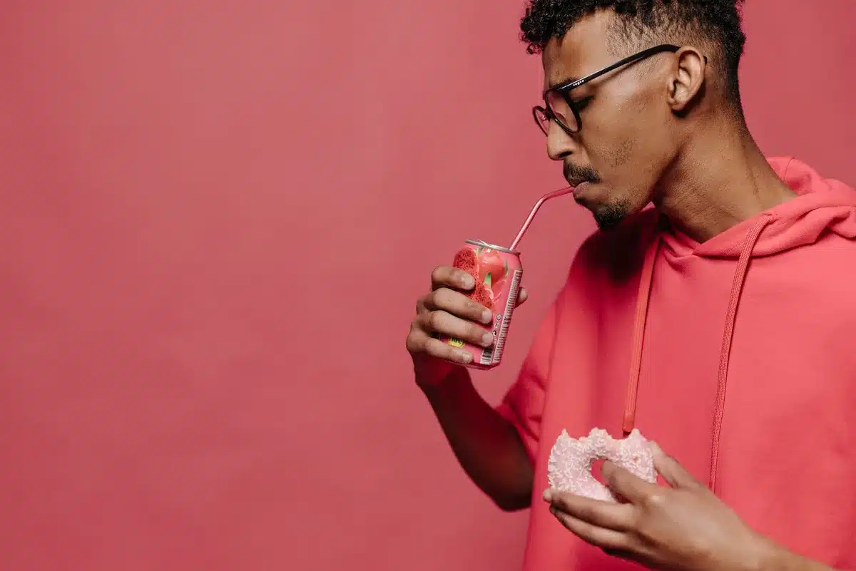 Jugendlicher trinkt aus einer Dose mit zuckerhaltiger Limonade